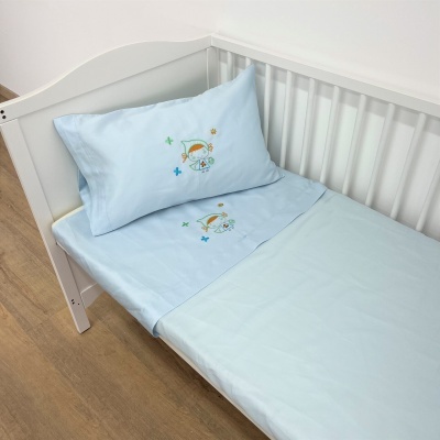 Roupa de cama infantil azul claro com bordado de balão e animal, em cama branca