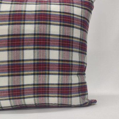 Almofada xadrez em vermelho, branco, azul e amarelo sobre superfície branca