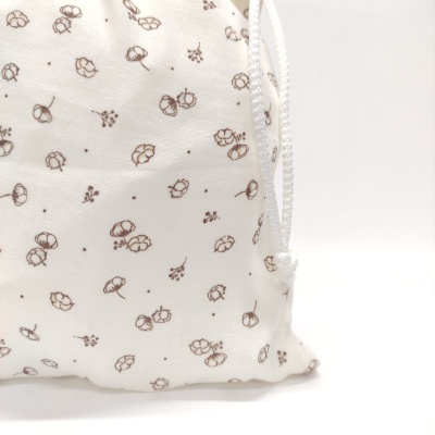 Saco de tecido branco com padrão castanho de flores e frutos pequenos