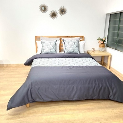 Cama de madeira com roupa de cama cinza e branca e mesa de cabeceira com vaso e flores
