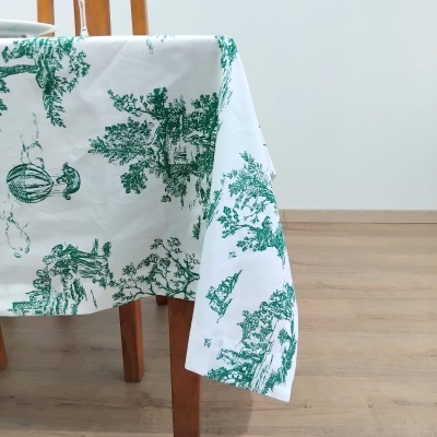 Toalha de mesa branca com padrão verde em mesa de madeira