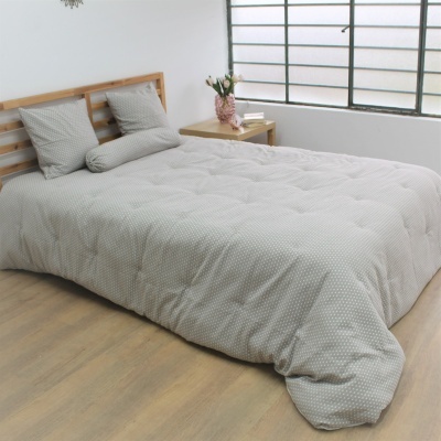 Cama com edredão cinza claro com bolinhas brancas e almofadas combinando num quarto com janela grande e mesa de cabeceira