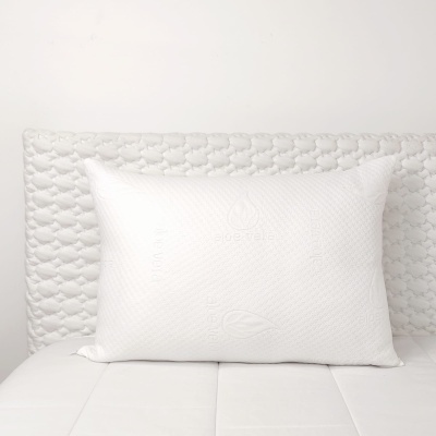 Travesseiro branco texturizado sobre cama branca com cabeceira acolchoada branca