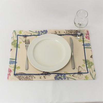 Jogo americano floral com prato branco, talheres de metal e taça de vidro