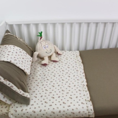 Cama de criança branca com lençóis bege e peluche