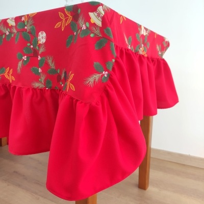Toalha de mesa vermelha com padrão floral natalício e saia franzida cobrindo mesa de madeira