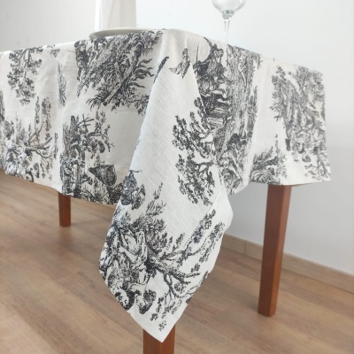 Toalha de mesa branca com padrão preto de paisagens sobre mesa de madeira