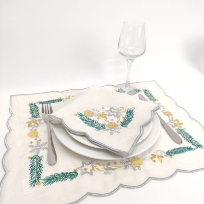 Conjunto de mesa branco bordado com motivos natalícios, garfo, prato branco e taça de vidro.