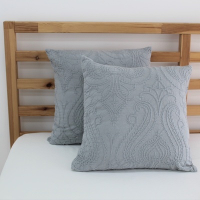 Almofadas cinza em cama com cabeceira de madeira clara