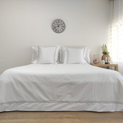 Cama de casal com roupa de cama branca e relógio de parede