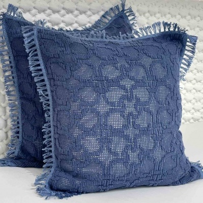 Duas almofadas quadradas azul-escuras com padrão de croché e franjas nas bordas