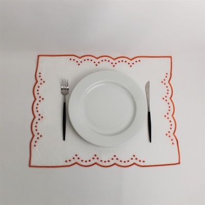 Conjunto de jantar com placemat branco decorado, prato branco, garfo e faca com cabos pretos