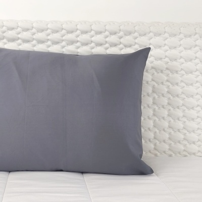 Almofada cinza sobre colchão branco acolchoado