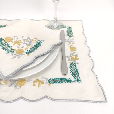 Jogo americano e guardanapo de linho branco bordado com motivos festivos verdes, dourados e prateados.