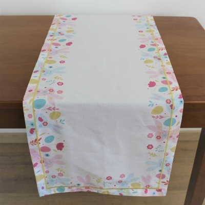 Caminho de mesa branco com padrão floral e de ovos coloridos pastel sobre mesa de madeira