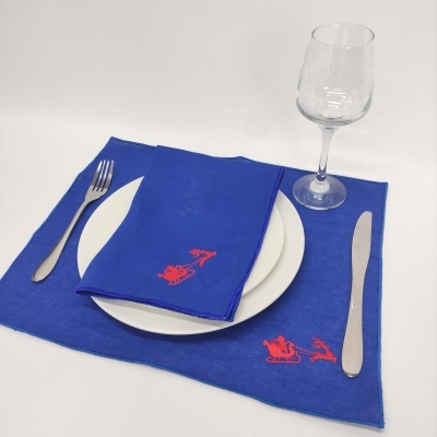 Conjunto de mesa azul com bordados vermelhos, prato branco, talheres metálicos e copo de vinho transparente