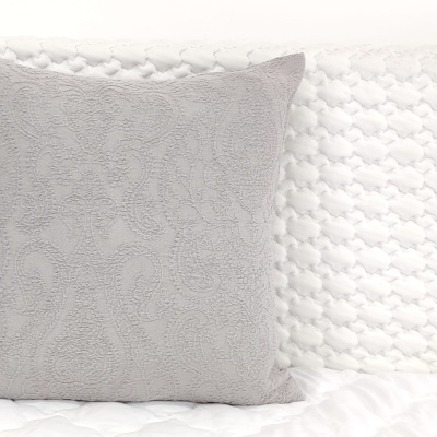 Almofada cinzenta texturizada sobre cama branca acolchoada