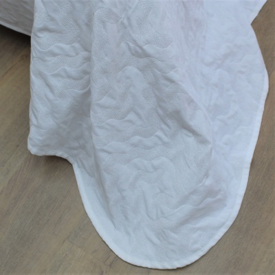 Tecido branco texturizado com padrão ondulado sobre piso de madeira clara