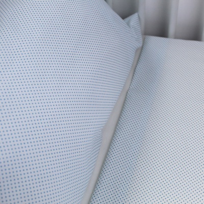 Almofadas brancas com padrão de pontos azuis em ambiente com cortinas claras