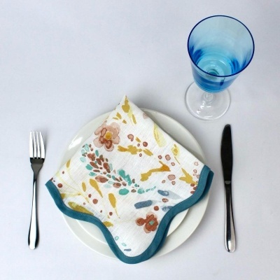 Mesa posta com prato branco, guardanapo floral e copo azul