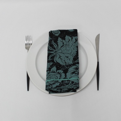 Guardanapo floral azul escuro e preto sobre prato branco com talheres pretos