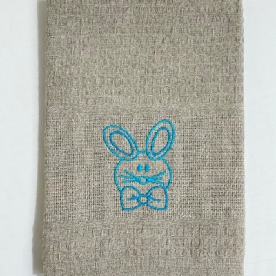 Toalha bege texturizada com bordado azul de coelho
