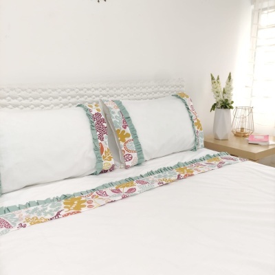 Roupa de cama branca com detalhes florais coloridos e riscas verdes