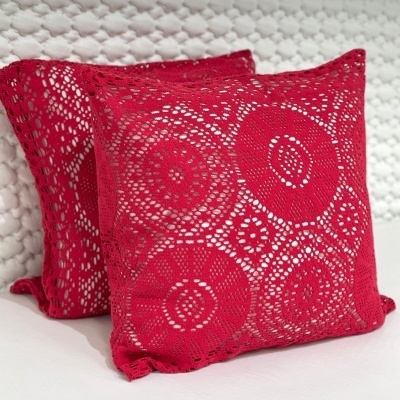 Duas almofadas vermelhas em croché com padrões circulares, sobre fundo branco.
