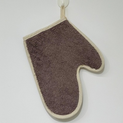 Luva de cozinha castanha e bege pendurada numa parede branca