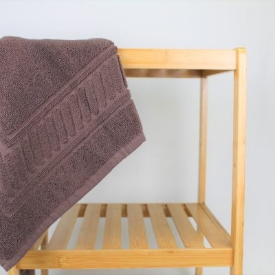 Toalha de banho castanha pendurada numa cadeira de madeira clara