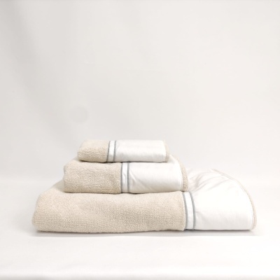 Conjunto de três toalhas bege e branco empilhadas com bordas prateadas