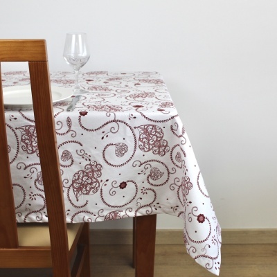 Toalha de mesa branca com padrões castanhos sobre mesa de madeira com cadeira