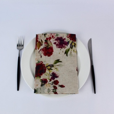 Guardanapo com padrão floral sobre prato branco com talheres pretos ao lado