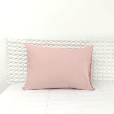 Almofada cor-de-rosa sobre cama branca com cabeceira acolchoada texturizada