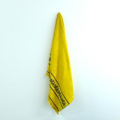 Toalha amarela com borda preta pendurada numa parede branca