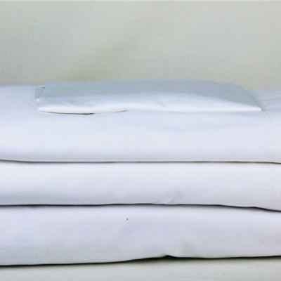 Conjunto de roupa de cama branca dobrada sobre fundo cinza claro