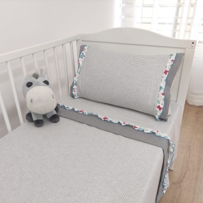 Cama infantil com roupa de cama cinza riscada e peluche de cavalo