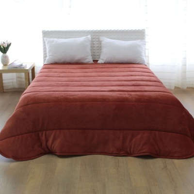 Cama com edredão vermelho alaranjado, almofadas brancas e cabeceira branca entrelaçada