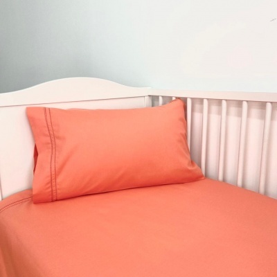 Cama de bebé branca com roupa de cama laranja