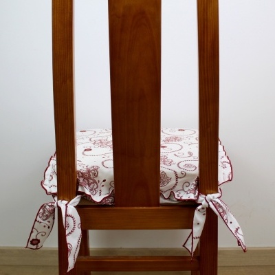 Cadeira de madeira com capa de assento branca com desenho bordô