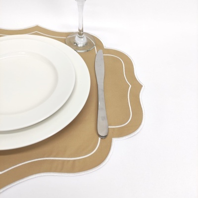 Placemat castanho com borda branca, prato branco, faca de metal e copo de vidro