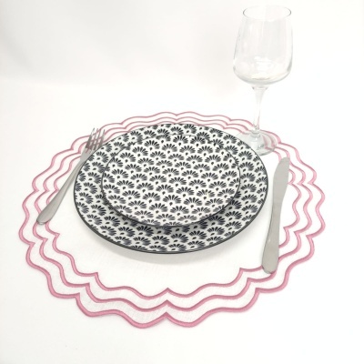 Conjunto de jantar com pratos decorados, talheres, copo e base rosa