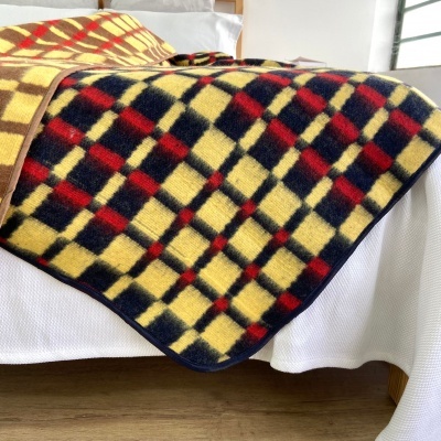 Cobertor quadriculado em amarelo, vermelho e azul sobre sofá branco
