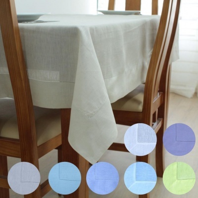 Toalha de mesa retangular branca com padrão bordado pendurada em mesa de madeira com cadeiras