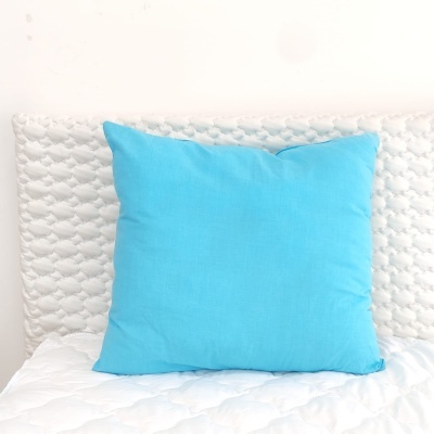 Almofada azul clara sobre colchão branco acolchoado com cabeceira branca