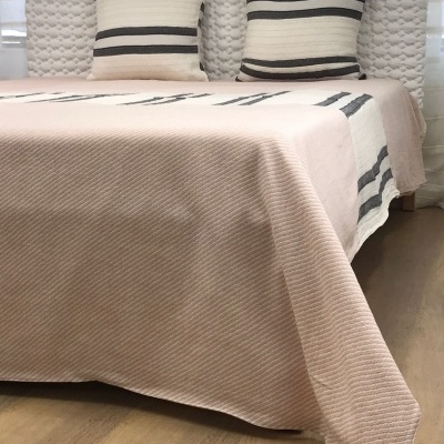 Cama com cabeceira estofada branca, colcha rosa com listras pretas e almofadas listradas pretas e creme