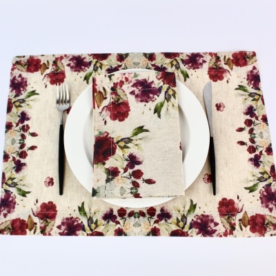 Jogo americano e guardanapo em tecido com padrão floral e talheres sobre fundo branco