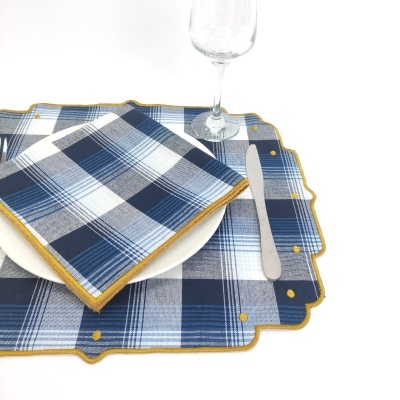 Guardanapos e individuais xadrez azul, branco e cinza com bordas amarelas em prato branco com faca e taça