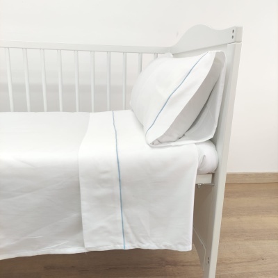 Cama infantil de madeira branca com roupa de cama branca e riscas azuis