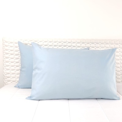 Almofadas azuis claras em cama branca com cabeceira texturada